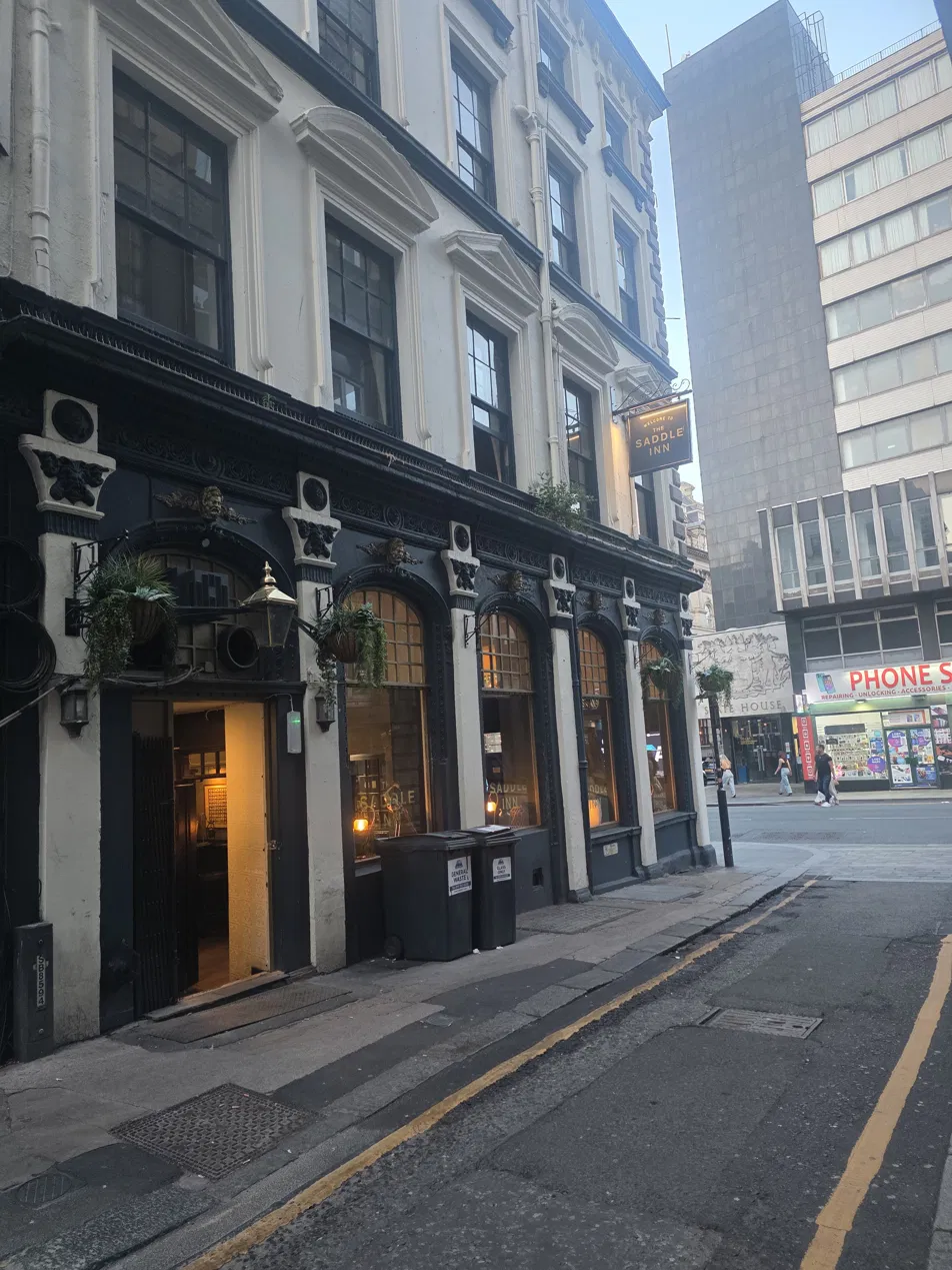 Side view of The Saddle Inn showing the hanging pub sign and ornate Victorian architecture