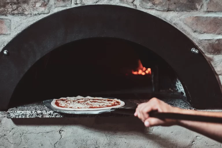 Margherita pizza going into a wood-fired oven